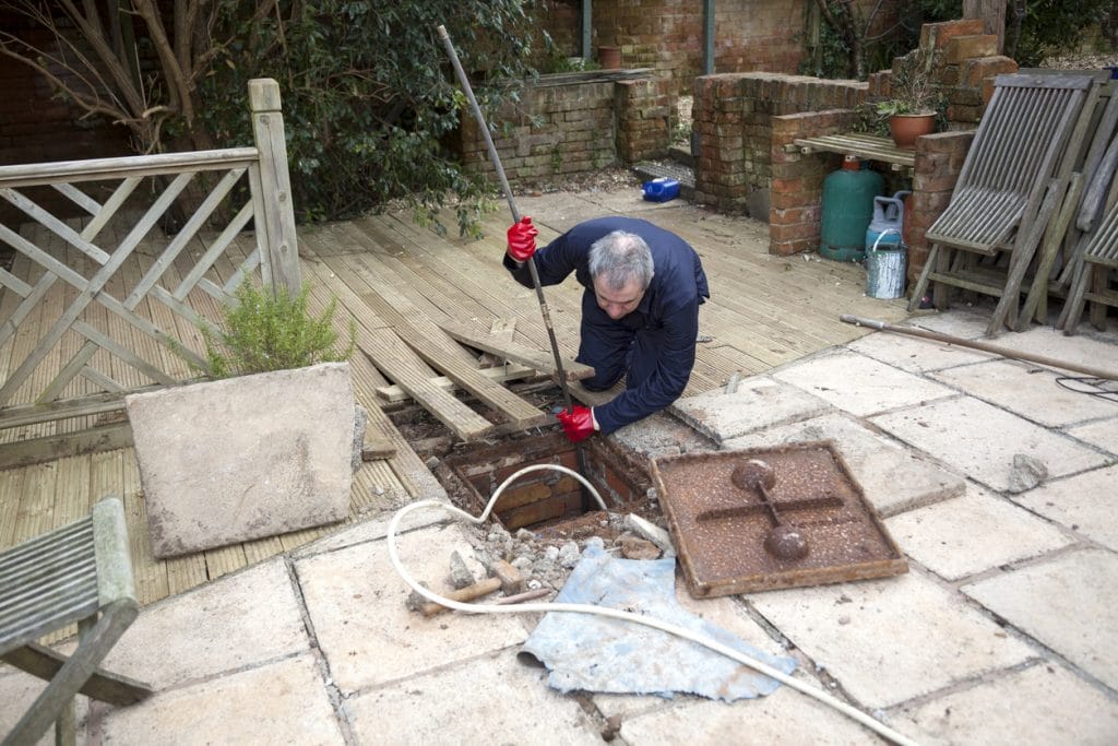 Male plumber unclogging a home's sewer stack clog using special equipment.