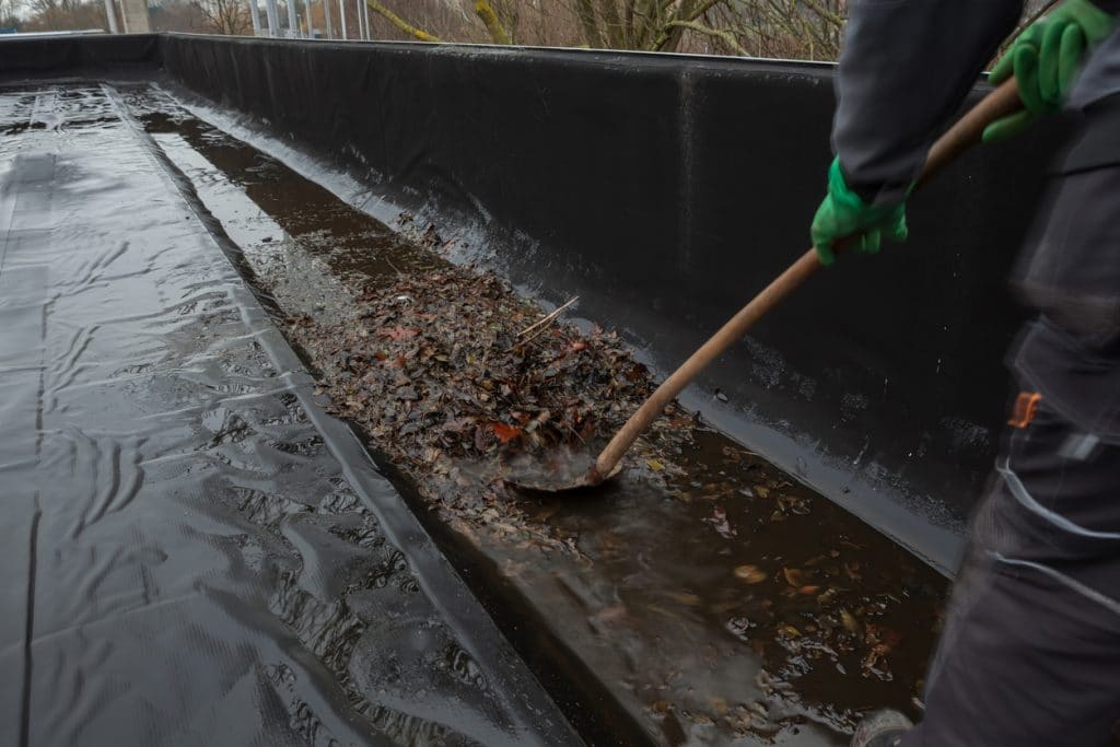 Professional plumber cleaning out a commercial building's roof drain.