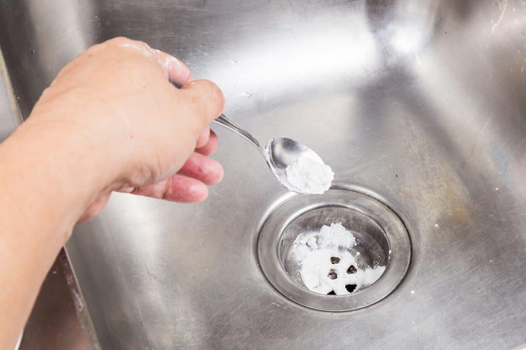 Clogged drain maintenance, person putting baking soda and vinegar solution to her sink drain.