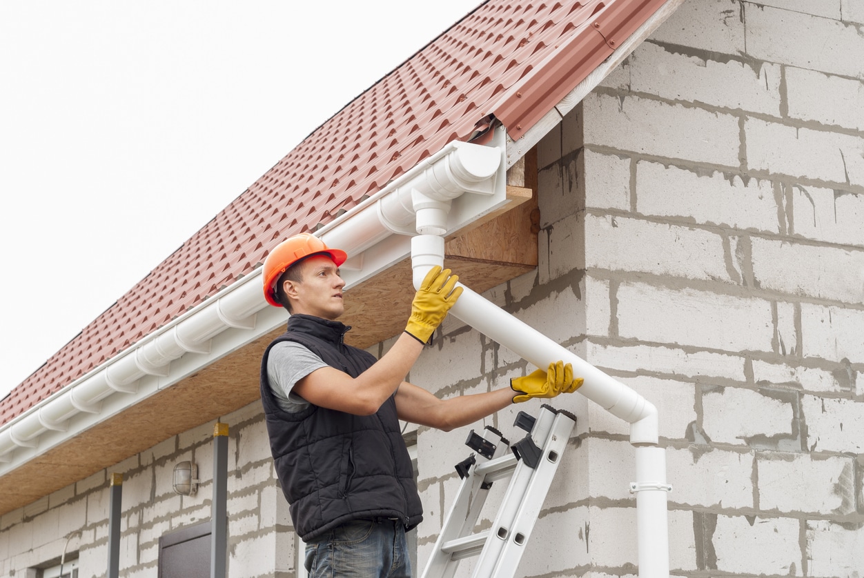 Male plumber checking a home's pipes and gutters - proper fall drain line backups solution.