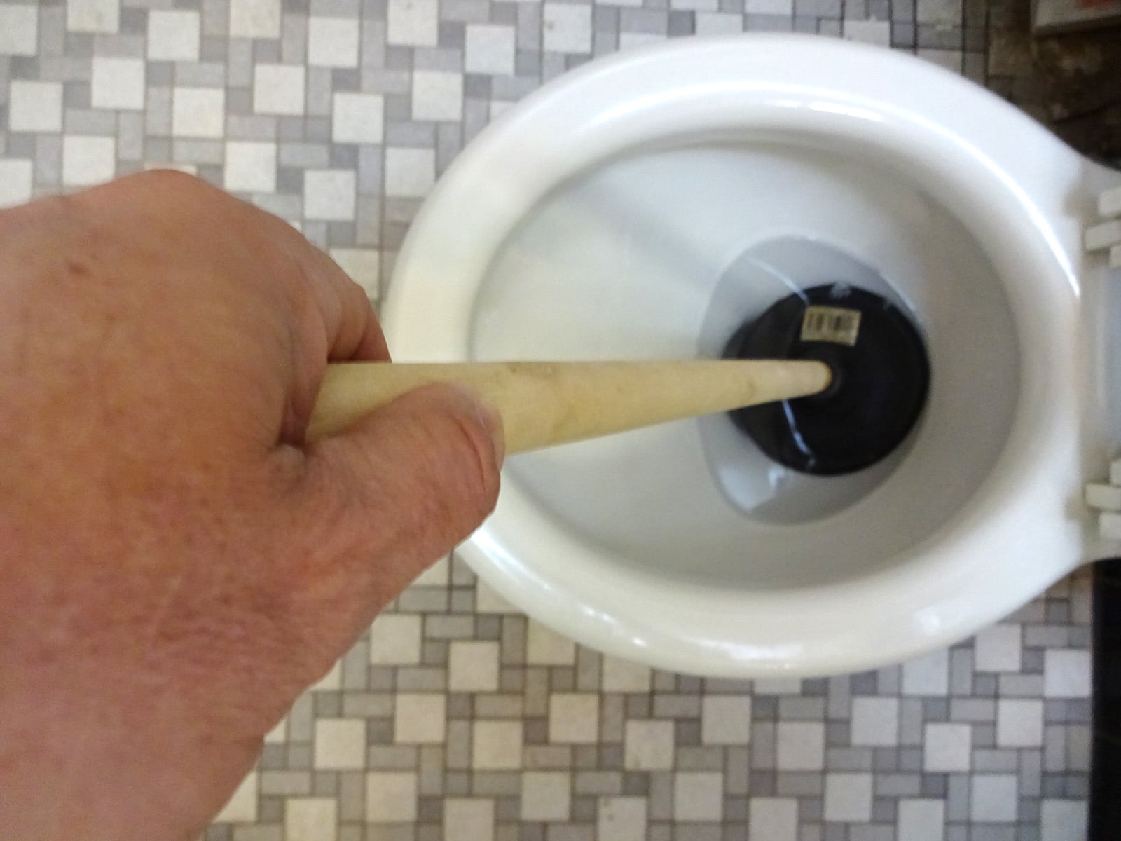 Clearing a toilet clog with a plunger.