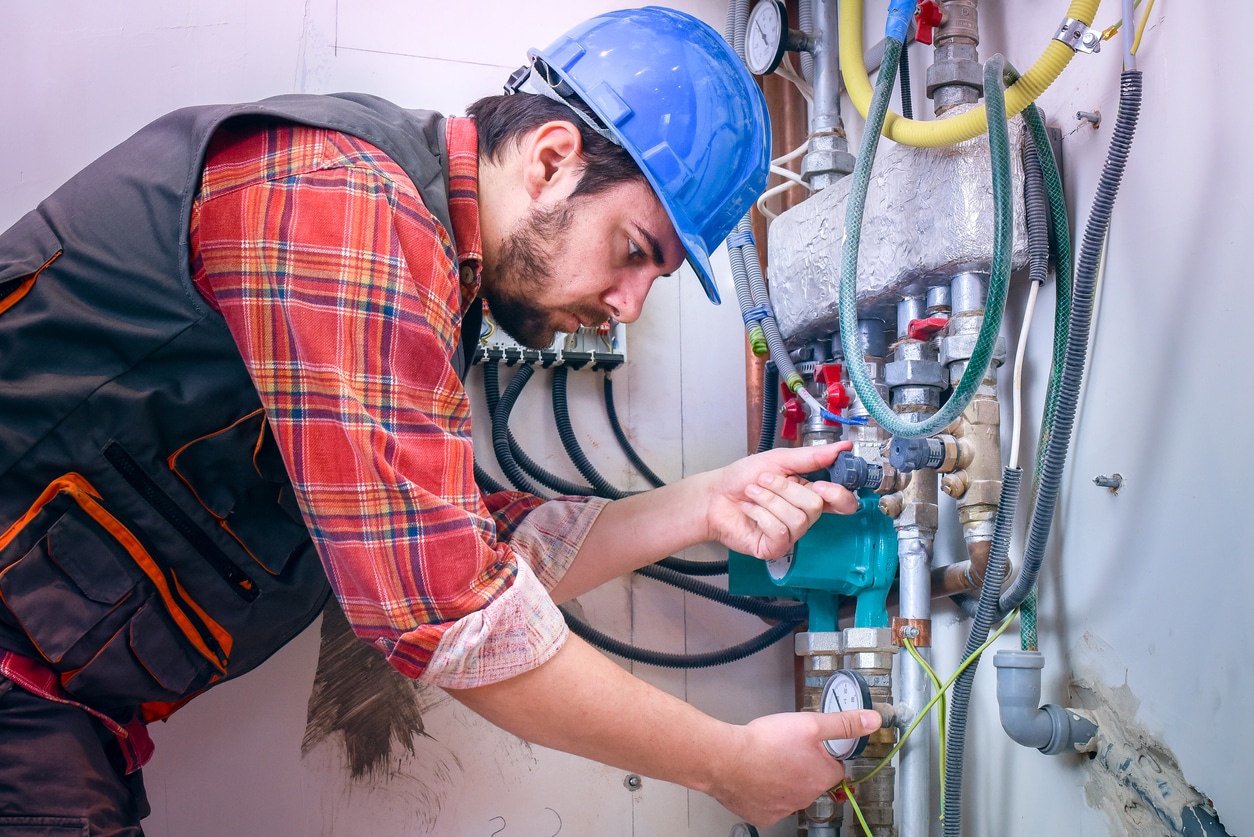 Male plumber installing a sewer alarm in a residential plumbing system.