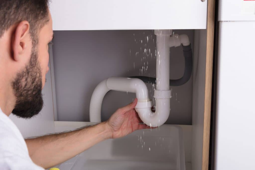 Male plumber checking a sink pipe leakage and integrity of the trap's water seal.