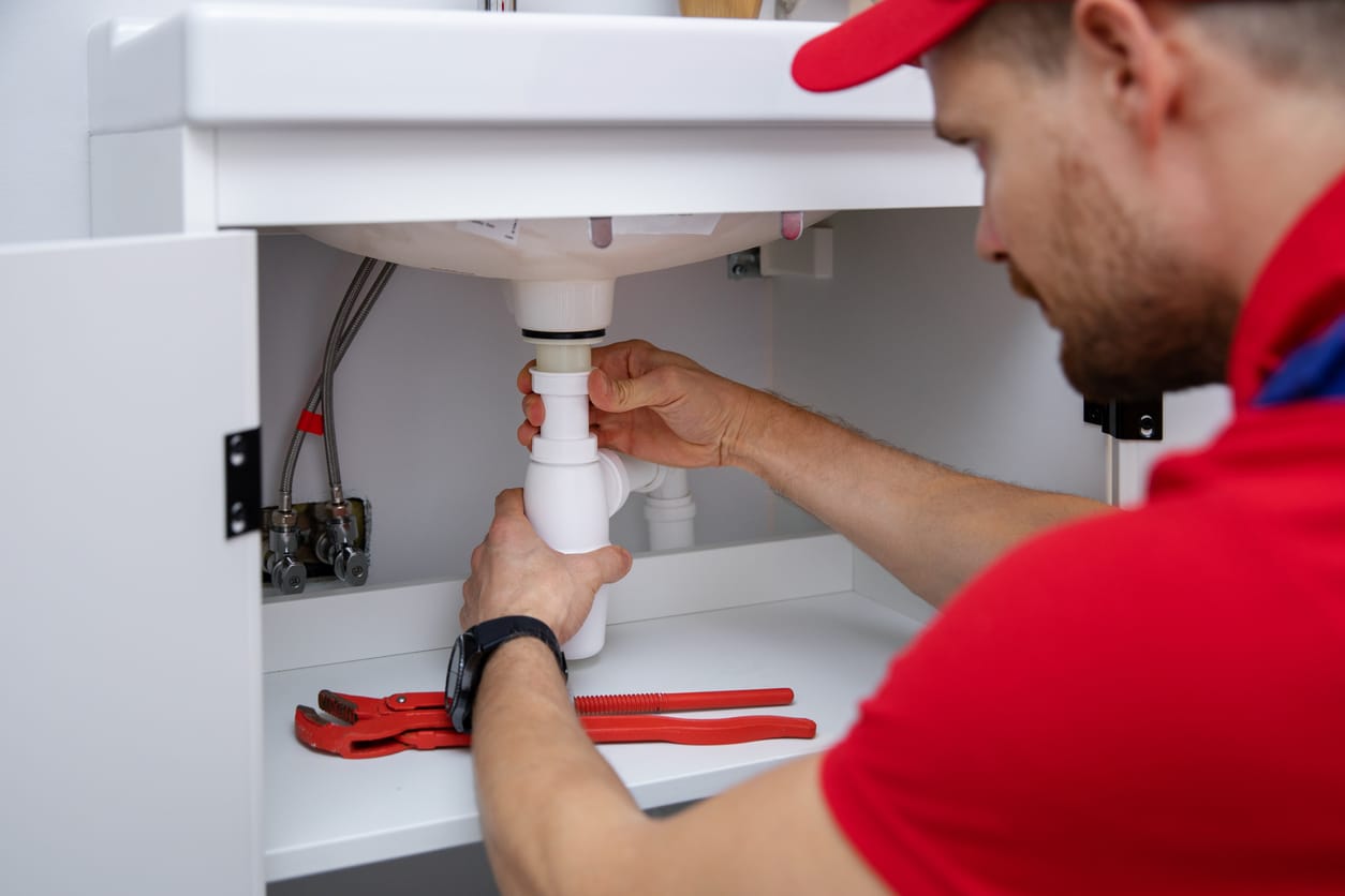 Male plumber providing emergency drain services for a residential home, using special tools to solve drain problems.