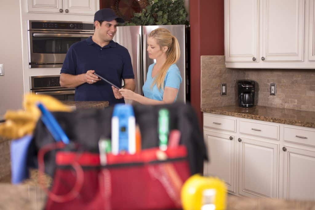 Male plumber explaining services to a female customer - drain cleaning service in Queens.