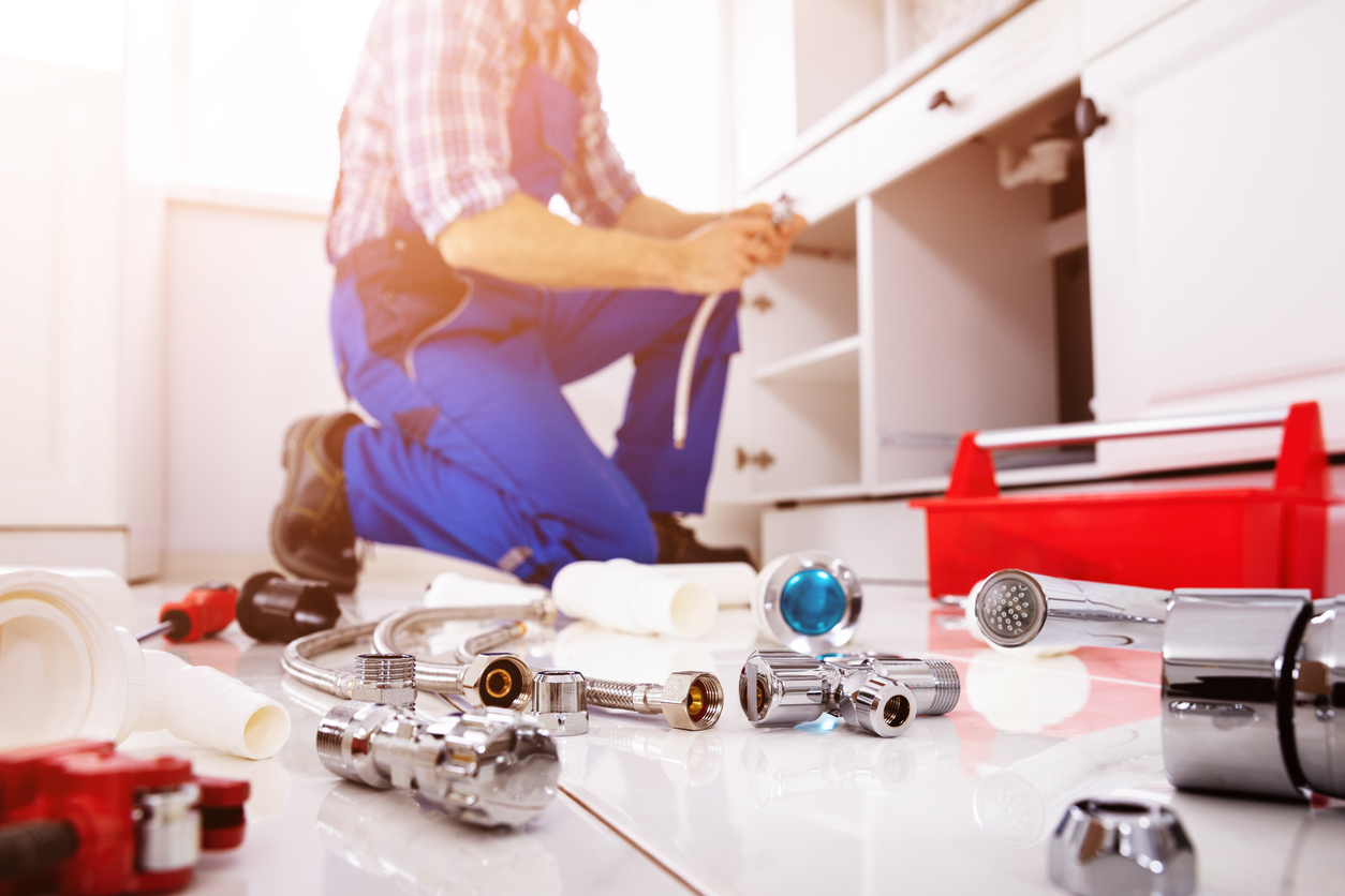 Male plumber fixing a home's piping system using different tools - drain cleaning services in Manhattan.