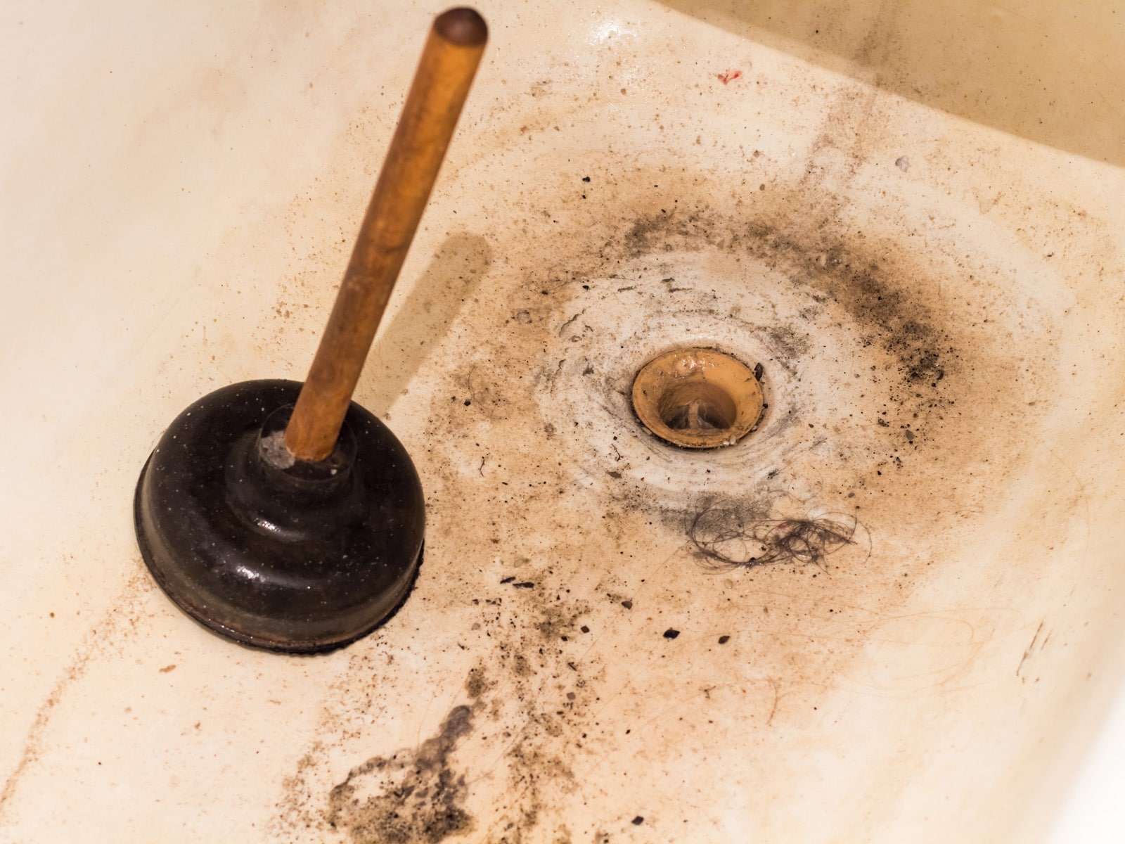 A plunger inside a shower to clean a shower drain.