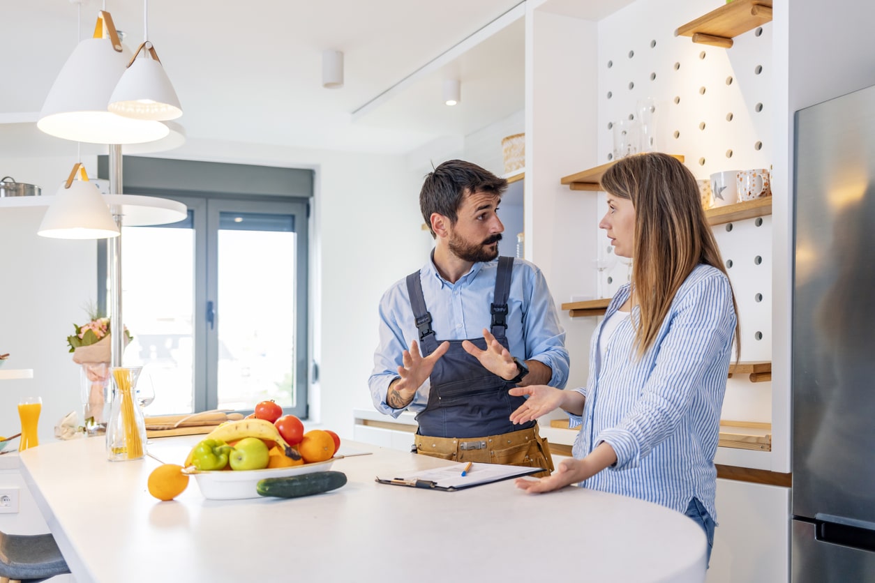 Housewife speaking with a male plumber about the plumbing services that her home needs - discussing about fair drain cleaning cost.