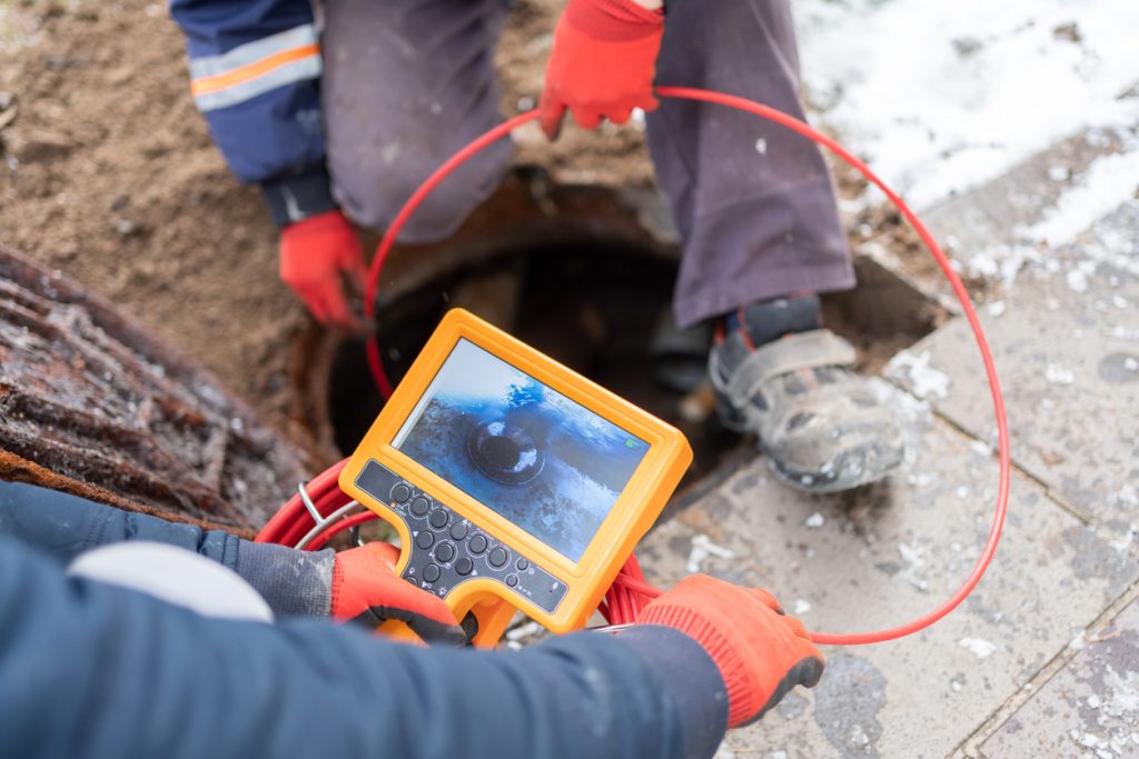 Drain cleaning experts - Two professional plumbers using a drain camera to diagnose sewer line problems.